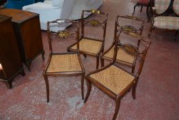 A set of four Regency brass inlaid chairs with cane seats.