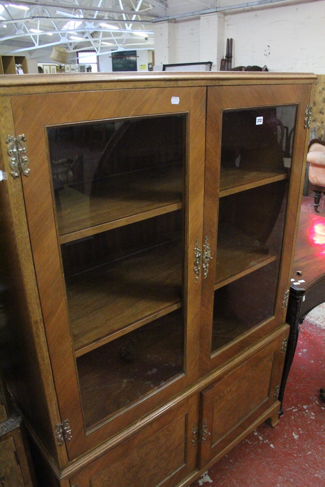 A Queen Anne style walnut china cabinet, with glazed top section on cupboard base and bracket feet