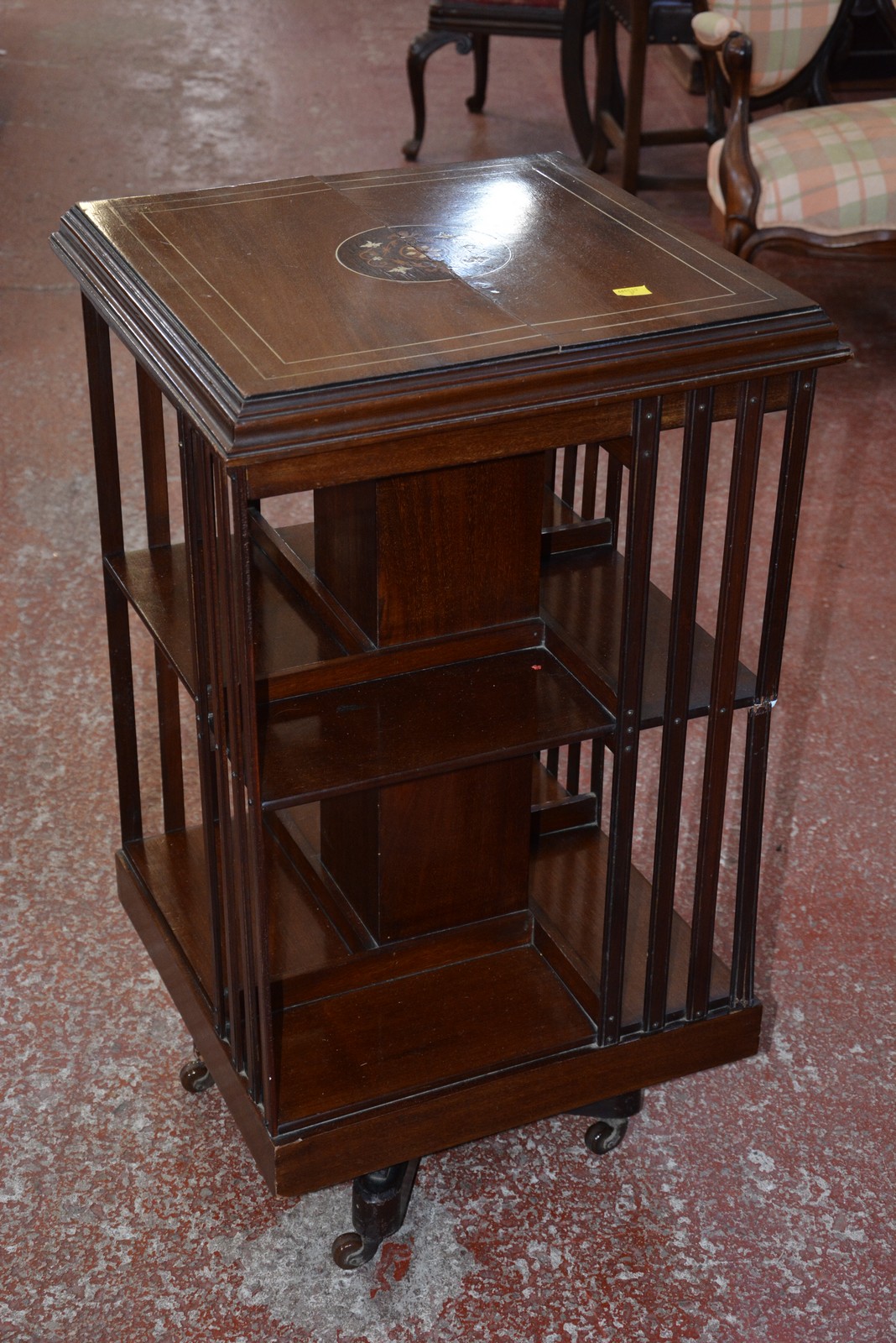 An Edwardian revolving bookcase with a floral inlaid top. (Crack to top)
