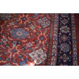 A North West Persian style rug with stylized decoration to the madder central field