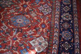 A North West Persian style rug with stylized decoration to the madder central field