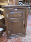 A late 18th/early 19th Century oak corner cupboard, the fielded panelled doors enclosing shelves,