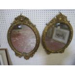 A pair of gilt composition oval mirrors, with scroll and leaf decoration 74cm high,