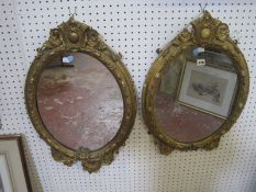 A pair of gilt composition oval mirrors, with scroll and leaf decoration 74cm high,