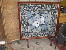 A modern reproduction firescreen, the panel inset with floral needlework 120cm high, 110cm wide,