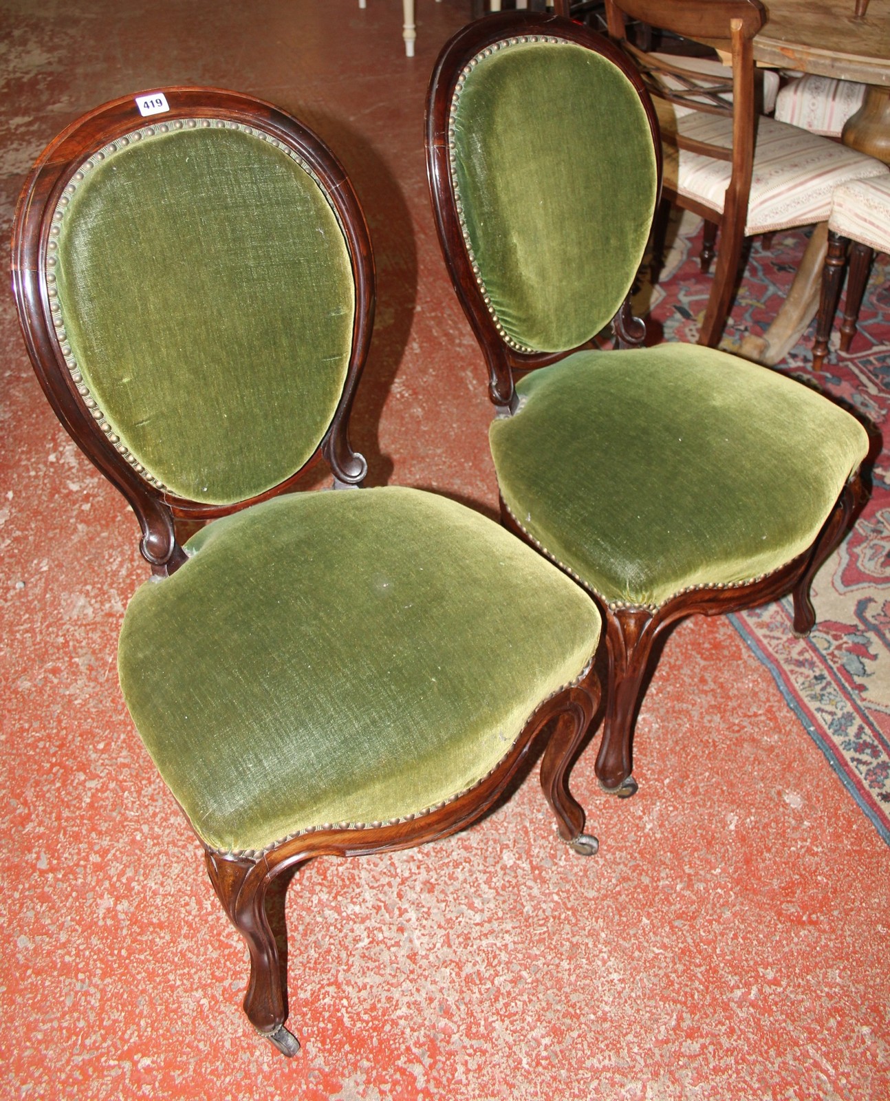 A set of four Victorian rosewood dining chairs with upholstered backs and seats on cabriole legs.