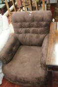 A brown upholstered armchair on turned legs