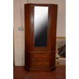 An Edwardian walnut corner wardrobe with mirrored door over drawers.