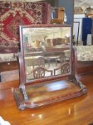 A late Georgian mahogany vanity mirror the plate held in two serpentine supports.