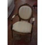 A Louis XVI style armchair in cream striped upholstery.
