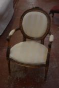 A Louis XVI style armchair in cream striped upholstery.