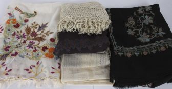 A black embroidered wool shawl; together with a black silk stole; a cream embroidered shawl; and