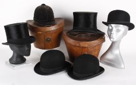 Two black silk top hats in leather hat boxes, both with a circumference of 22in; together with three