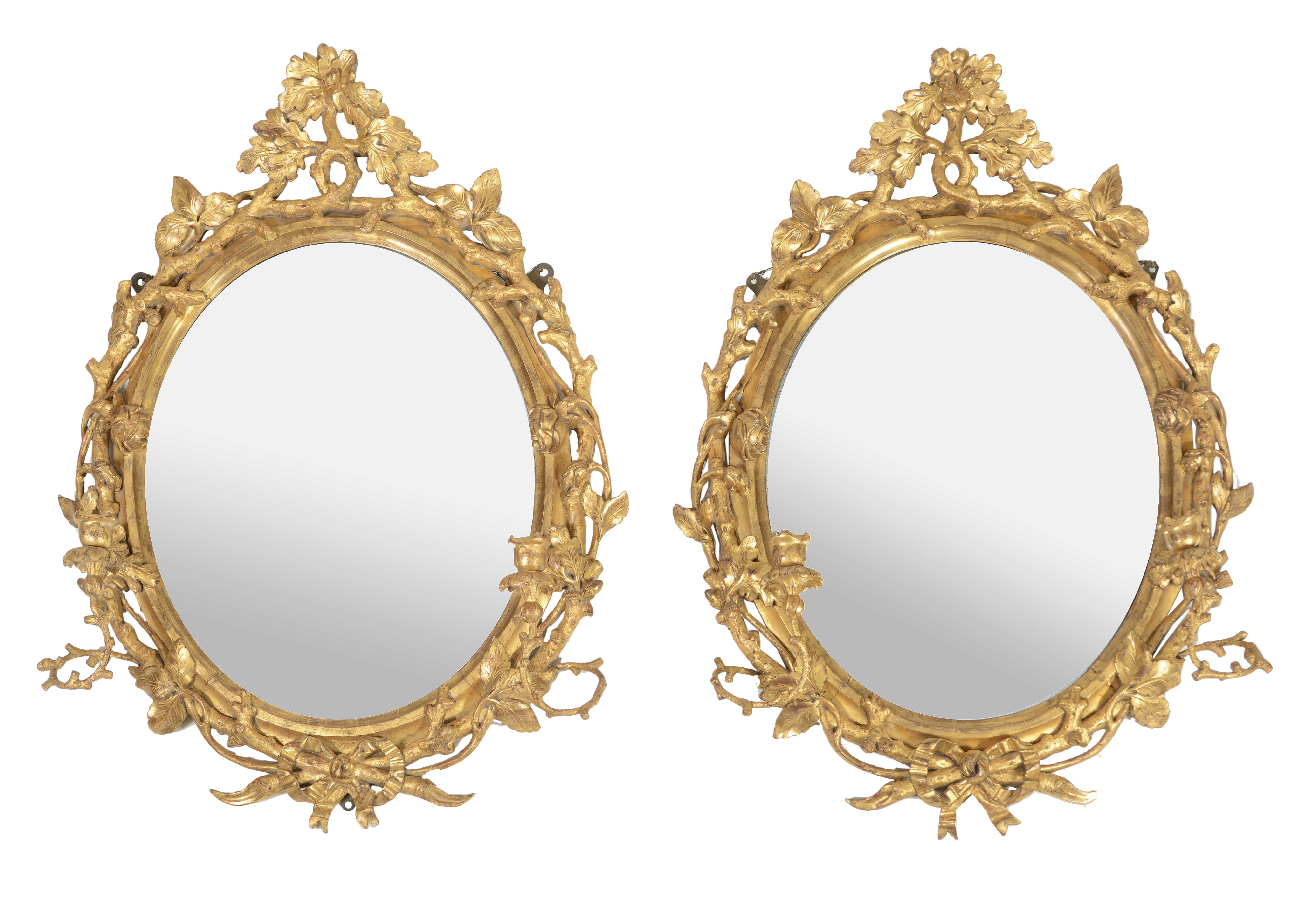 A pair of George III carved giltwood oval girandole wall mirrors, circa 1760 A pair of George III