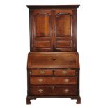 A George III oak and mahogany crossbanded bureau bookcase, the dentil moulded cornice above a pair