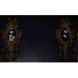 Pair of gilt metal twin light wall appliqués, each with shaped mirror back surrounded with