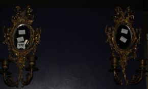 Pair of gilt metal twin light wall appliqués, each with shaped mirror back surrounded with