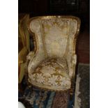 A Louis XVI style gilt frame and upholstered wing armchair