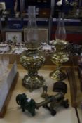 An ornate brass oil lamp, another, a model canon and two brass figures of Mr. Pickwick, one with