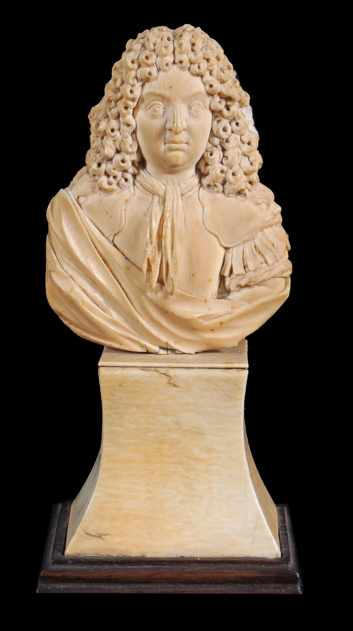 A relief carved ivory bust of a French nobleman, French, circa 1700, full face with long curly hair,