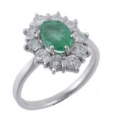 An emerald and diamond cluster ring, the central oval shaped emerald claw...  An emerald and diamond