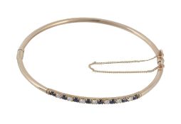 A sapphire and diamond bangle, set with alternating brilliant cut diamonds...  A sapphire and