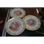 Three Royal Doulton cabinet plates, painted with roses and signed by C. Hart, within an elaborate