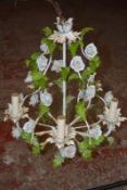 A painted metal and polychrome decorated ceramic mounted chandelier with floral decoration
