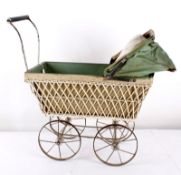 An early 20th century toy pram, with a white painted wicker body, green canvas hood, metal chassis