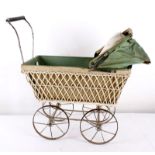 An early 20th century toy pram, with a white painted wicker body, green canvas hood, metal chassis