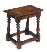 A late 17th century oak joint stool, with thumb moulded top, reeded rails and baluster turned