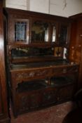 A late Victorian oak dresser with a mirrored back flanked by stain glass cabinets, richly carved