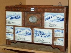 A early 20th Century Continental oak hanging kitchen cupboard, with clock, ceramic drawers, labelled