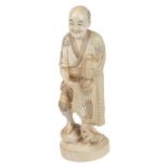 An Ivory Okimono of a Fisherman  , he stands on a rocky outcrop with waves crashing at his feet, he