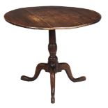 A George III oak tripod table,   the circular tilt top on turned stem with splayed legs and pad