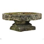 A French rough hewn circular millstone mounted onto an associated limestone...  A French rough