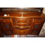 An Edwardian Aesthetic walnut serpentine sideboard with a central row of drawers flanked by