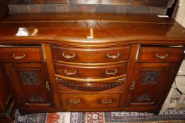 An Edwardian Aesthetic walnut serpentine sideboard with a central row of drawers flanked by