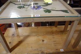 A small wooden table with a collage of glass representing a passion flower under