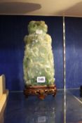 A Chinese carved green quartz vase and cover, with wooden stand, 31cm high