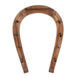 A stained wood coat rack, 20th century, in the form of horseshoe with lacquered brass nail pattern