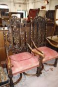 A near pair of Carolean style carved walnut open armchairs each with profusely carved back,