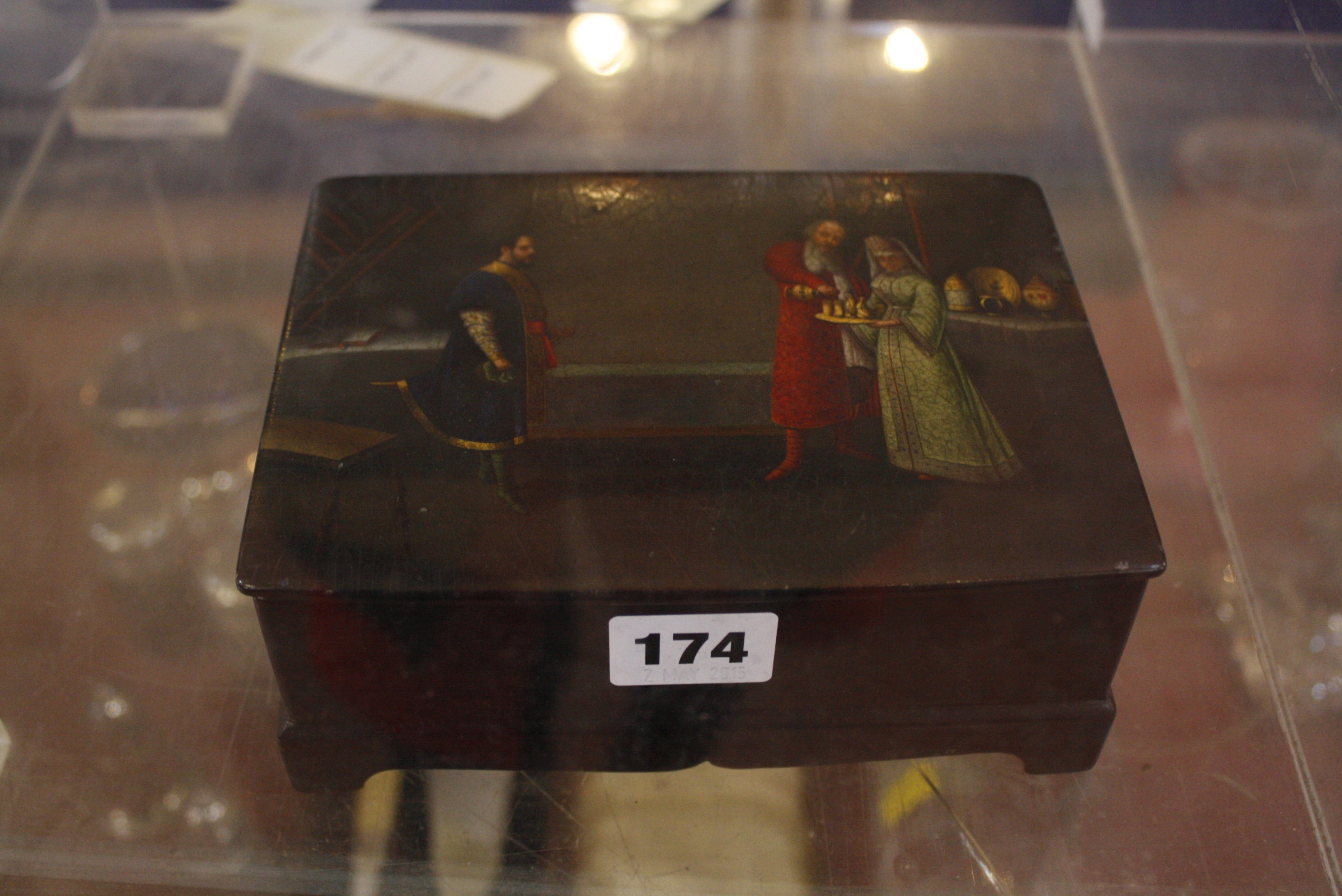 A Russian black lacquered box, decorated with interior scene to lid, with red inside, labelled