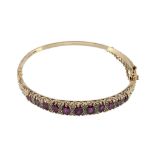 An 18 carat gold ruby and diamond hinged bangle  An 18 carat gold ruby and diamond hinged