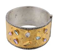 A gem set cuff bangle, the two colour broad hinged bangle set with various...  A gem set cuff