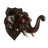 A Ceylonese carved and stained wood wall mounting model of an elephant  A Ceylonese carved and