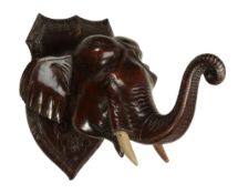 A Ceylonese carved and stained wood wall mounting model of an elephant  A Ceylonese carved and