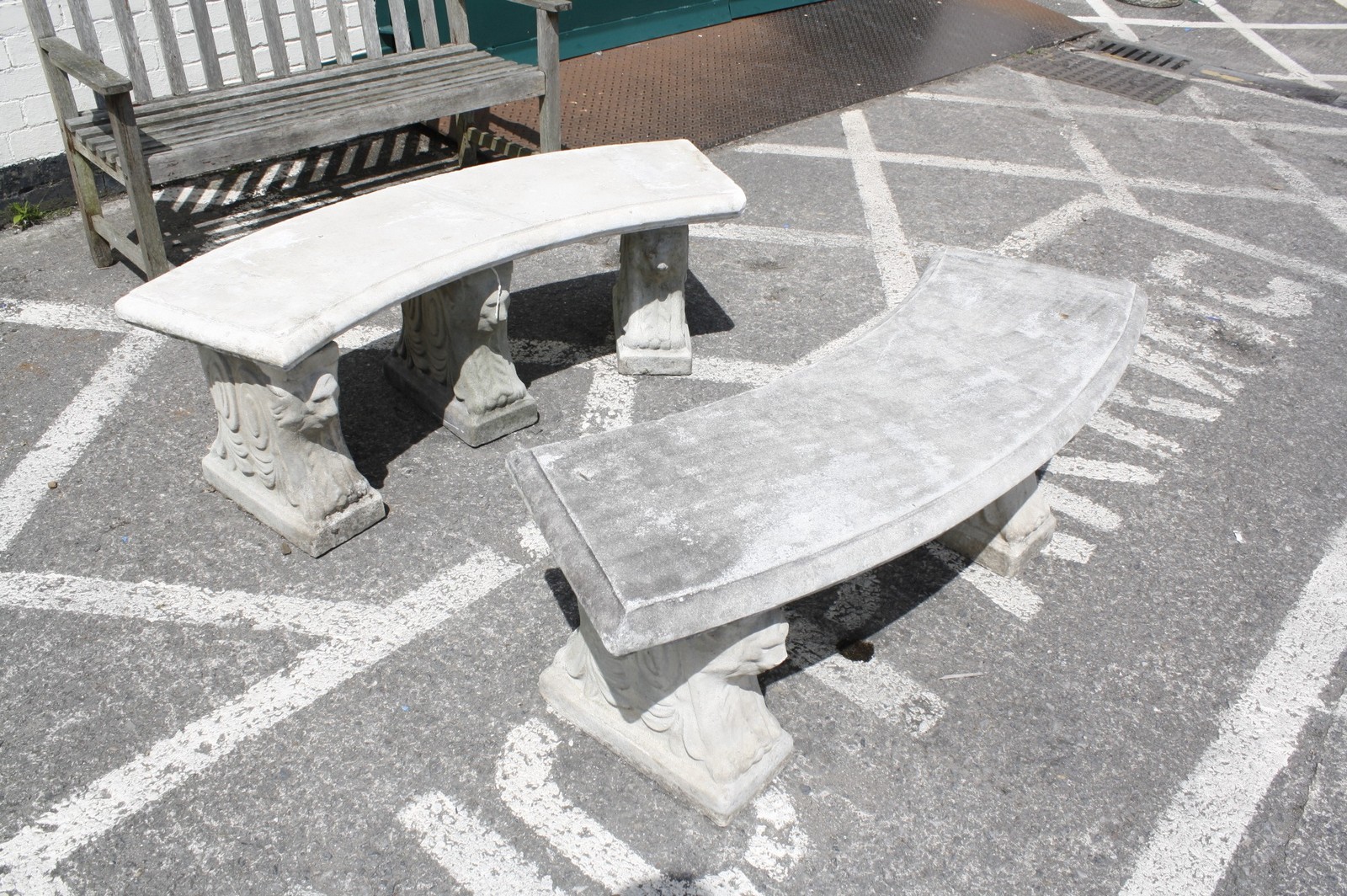 A pair of reconstituted stone curving garden benches, 20th century, each on three supports