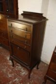 An Edwardian music cabinet with four drop front drawers and a small cabinet below.