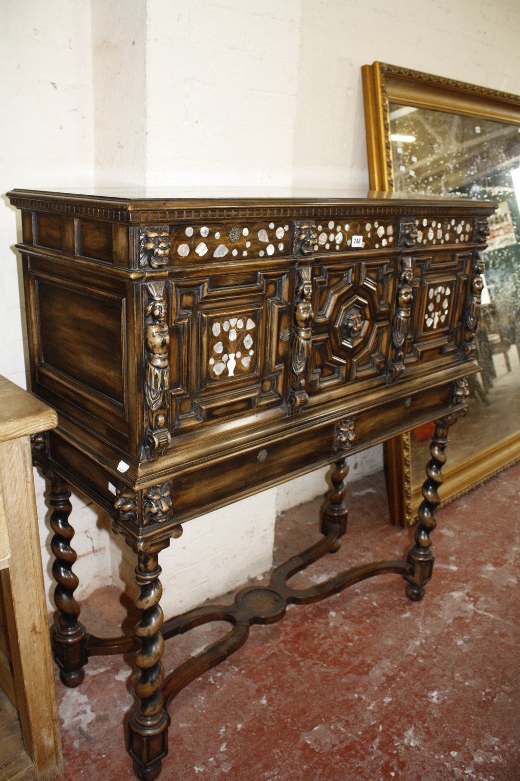 A Continental oak buffet with mother of pearl inlay, lion mask detail, raised on spiral supports.
